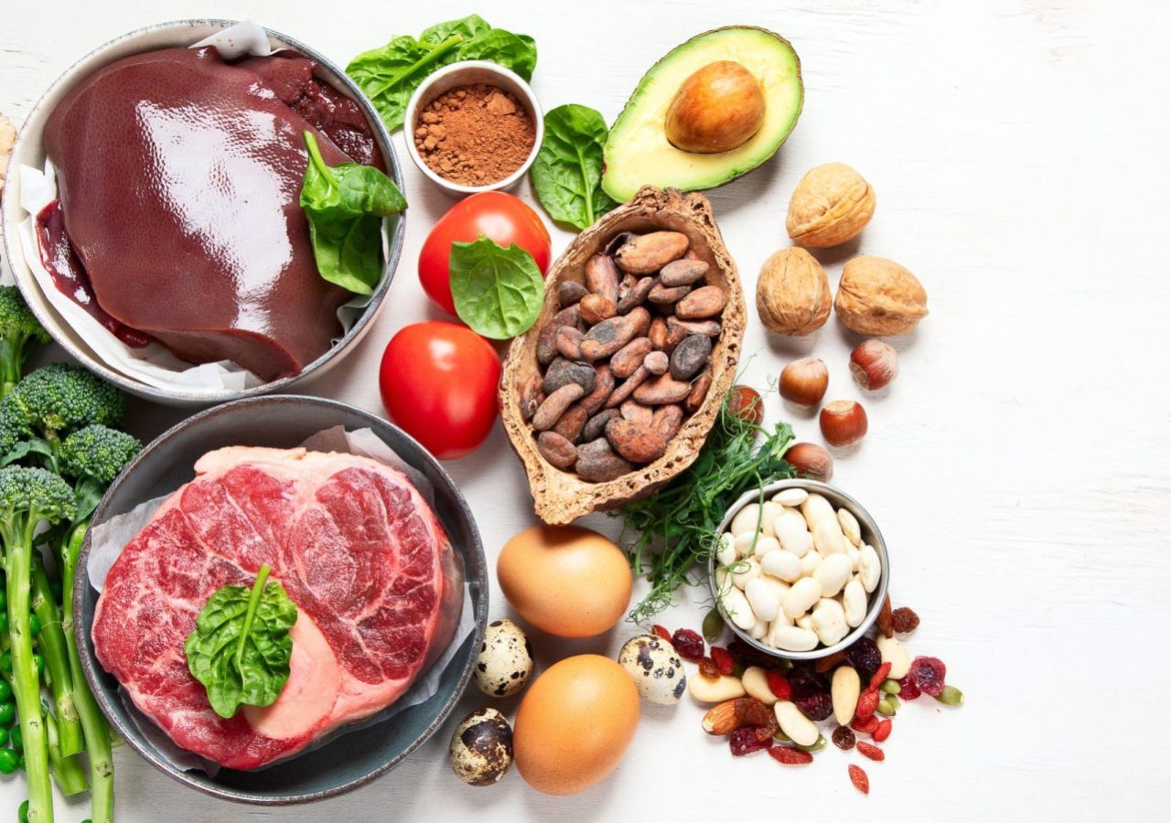 Food containing natural iron. Fe: Liver, avocado, broccoli, spinach, parsley, beans, nuts, on a white background. Top view. Panorama with copy space.