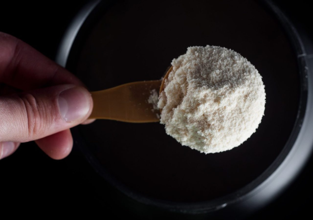 Sports Nutrition Powder. Soluble protein in a measuring spoon in a hand.